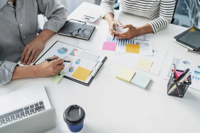 Analisi di grafici e dati economici da parte di due professionisti durante una riunione.